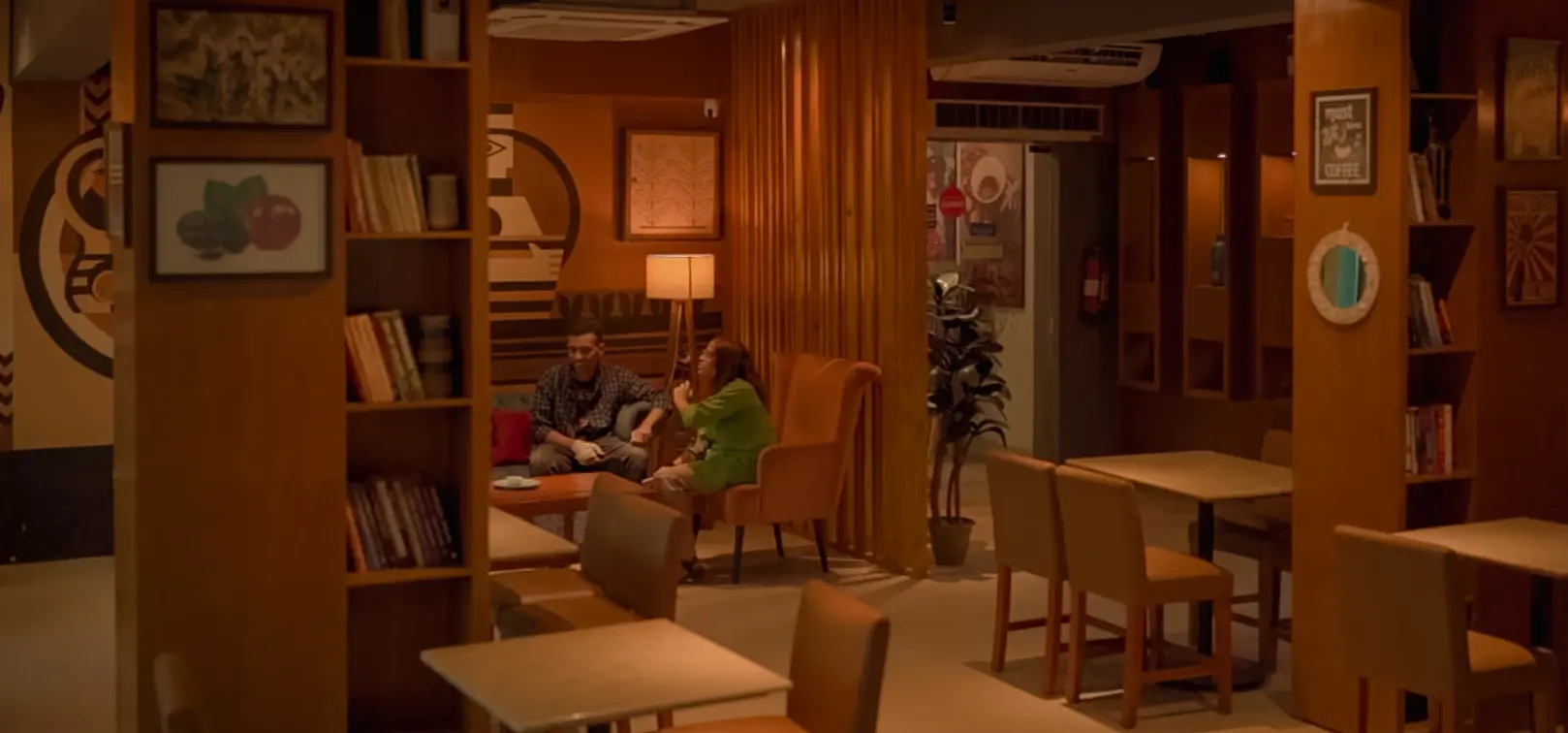 Wide view of tables, bookshelves and lounge seating inside Cafelytics