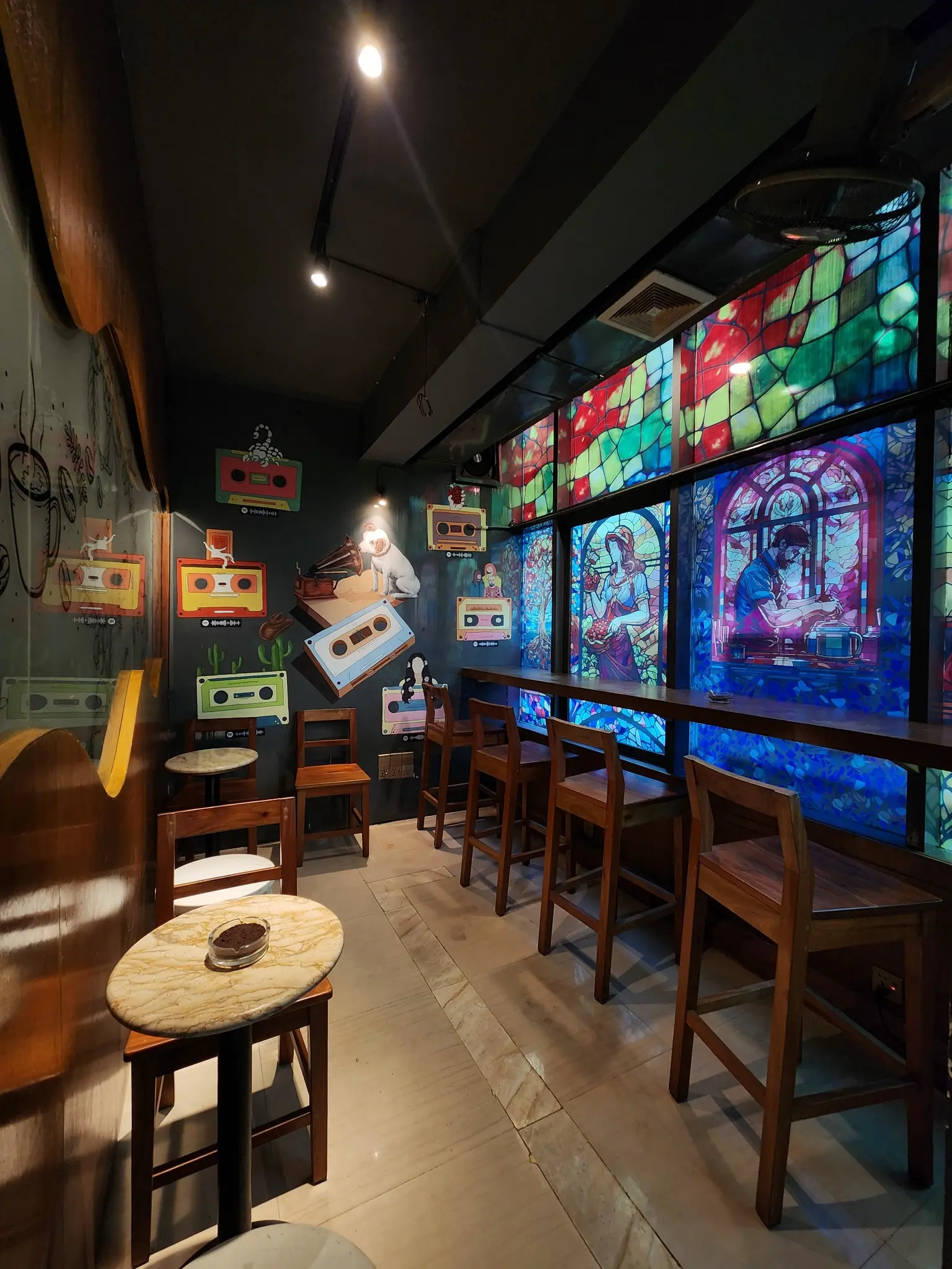 Tall view of the colourful window corner and wooden seating at Cafelytics