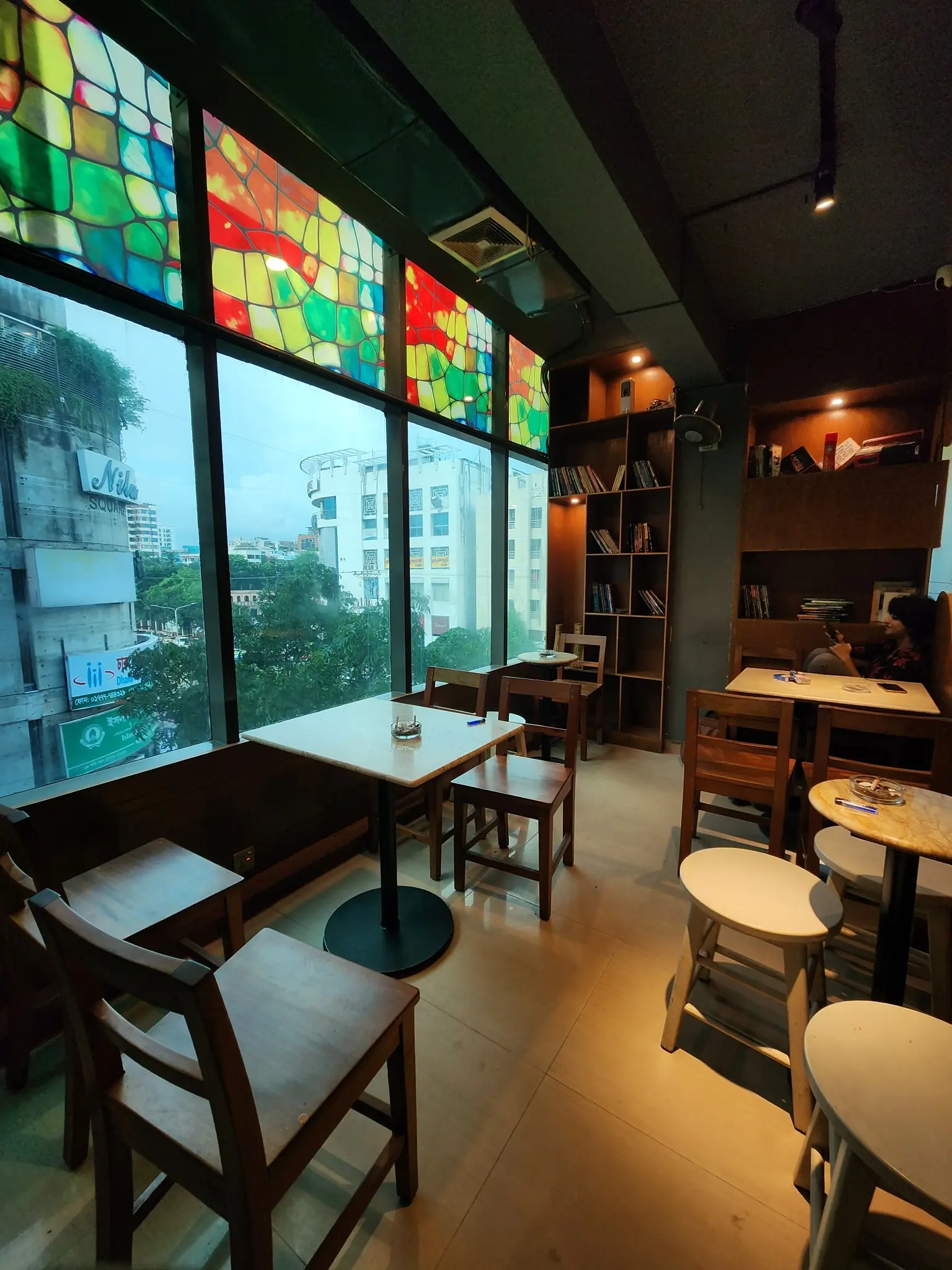 Window-side tables overlooking Dhanmondi from inside Cafelytics